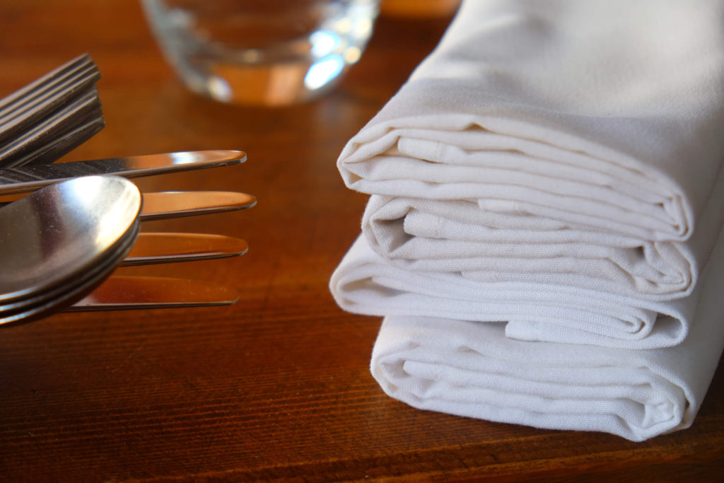Local restaurant linen supply napkins on a wood restaurant table..