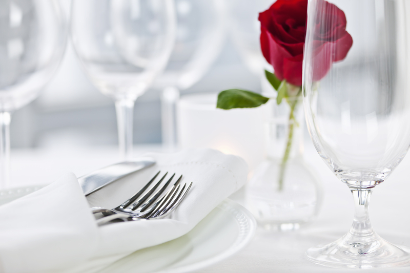 Classic white napkin with silverware in it next to a glass and rose. This article provides step-by-step instructions.